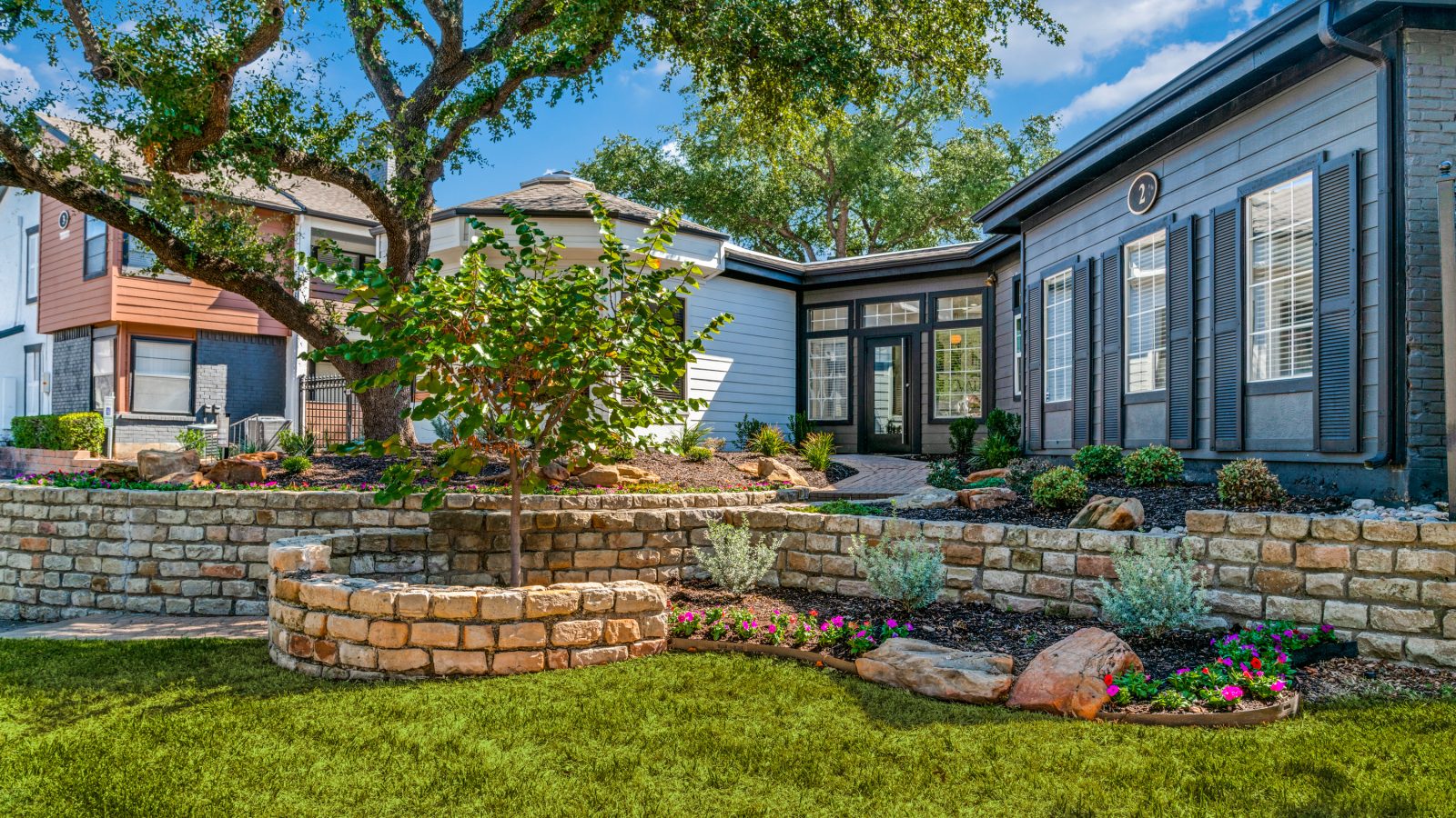 a home with landscaping and a stone wall at The Evaline